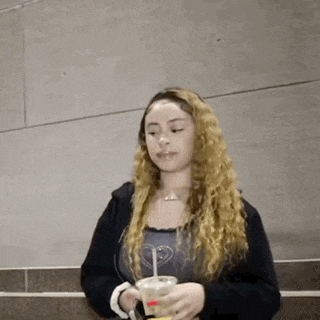 a woman with long curly hair is holding a cup of coffee .