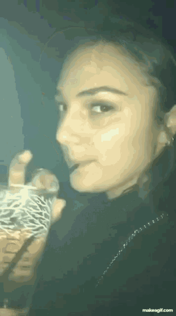 a woman drinking from a glass with a straw