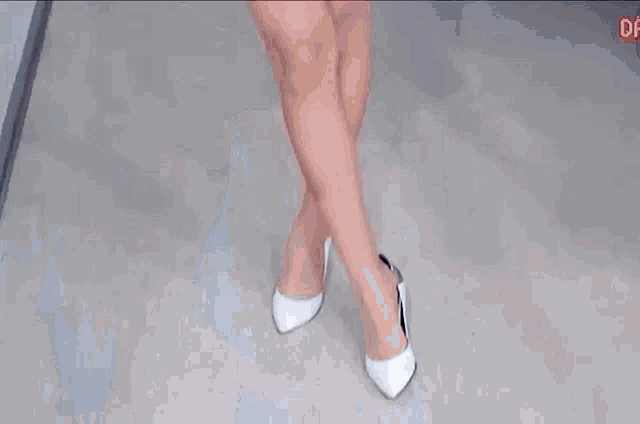 a woman in a white dress and heels is standing on a floor .