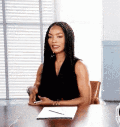 a woman is sitting at a table with a notebook and a pen on it .