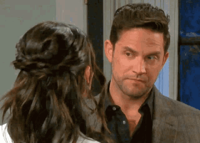 a man and a woman are looking at each other and the man is wearing a suit