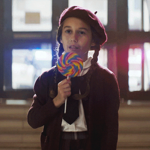 a girl in a beret is holding a lollipop in her hand