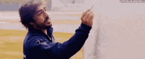 a man with a beard is writing on a piece of paper with a marker .