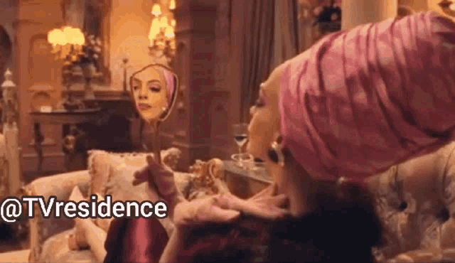 a woman is sitting on a couch looking at her face in a mirror .
