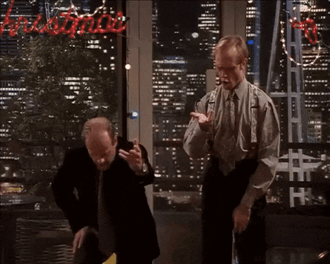 two men are dancing in front of a sign that says ' christmas ' on it