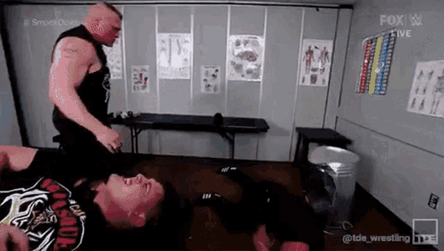 a man is laying on the floor while another man holds him up .