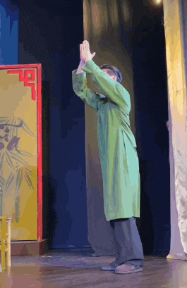 a man in a green coat is standing on a stage
