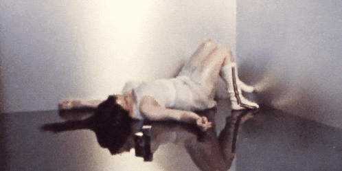 a woman in a white dress laying on the floor