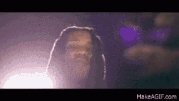 a man with long dreadlocks is standing in front of a purple background .