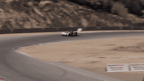 a race car is driving down a track with a castrol sign in the foreground