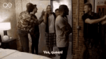 a group of people are standing in a room and one of them is saying yes , queen !