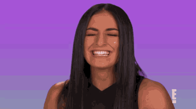 a woman is smiling in front of a purple background with the letter e