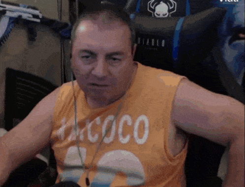 a man wearing an orange tank top that says coco on it