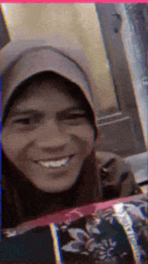 a woman wearing a hijab and a hat is smiling for the camera
