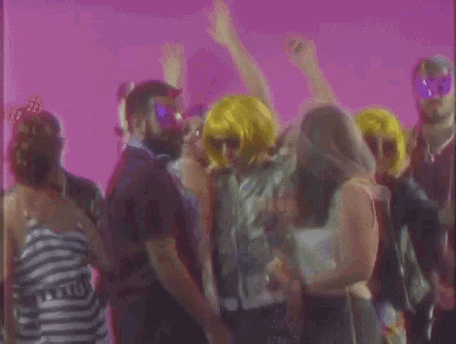 a group of people are dancing at a party while wearing sunglasses and wigs .