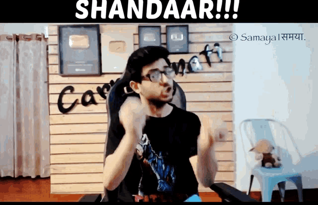 a man sitting in a chair with the words shandaar written on the top