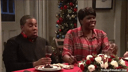 two people sitting at a table with a christmas tree in the background