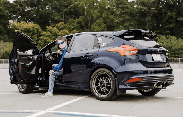 a man sits in the driver 's seat of a blue ford