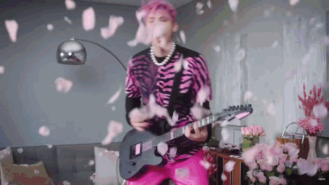 a man with pink hair is playing a guitar in a living room