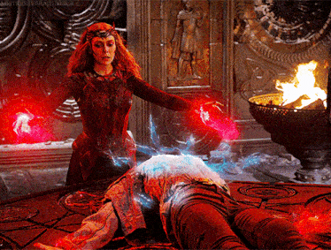 a woman in a red dress is standing next to a man laying on the ground