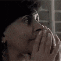a woman is covering her mouth with her hands and looking at something .