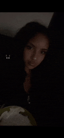 a woman is sitting in a dark room with a plate of food in front of her .