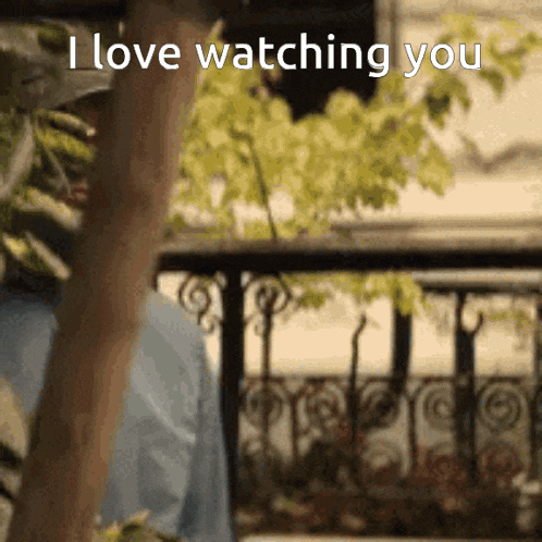 a person standing on a balcony with the words " i love watching you " written on the bottom