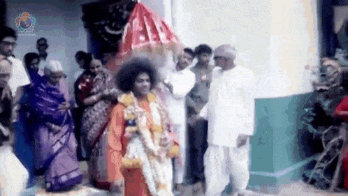 a group of people are standing around a man in a red robe holding a red umbrella .