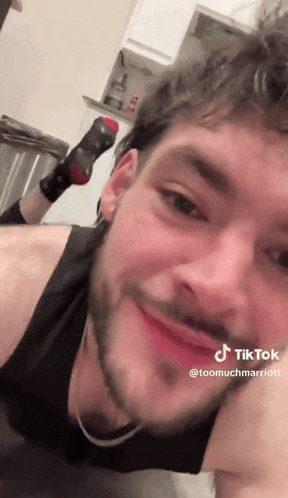 a man with a beard is laying on the floor with his feet up and smiling
