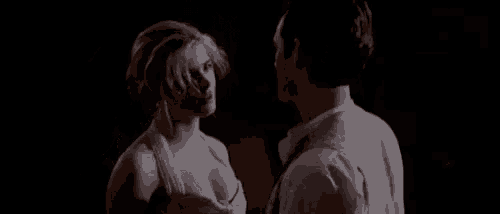 a man and a woman are looking at each other in the dark