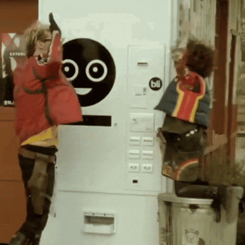 a woman in a red jacket is standing in front of a machine that has a bli sticker on it