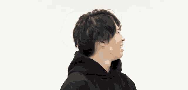 a man wearing a black hoodie is smiling and making a funny face
