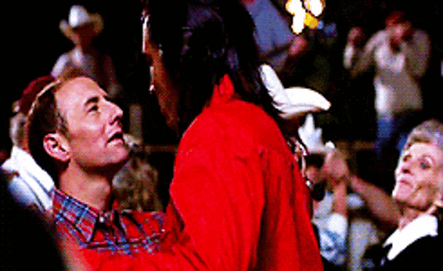 a man in a plaid shirt is dancing with a woman in a red jacket