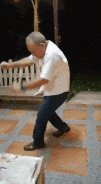 an elderly man is dancing on a tiled floor in front of a white fence .