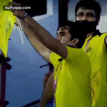 a man in a yellow shirt is holding a yellow flag in his hands .