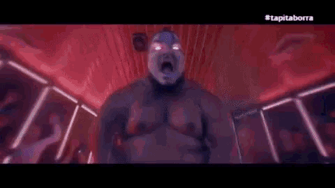 a man with a mask on his face is standing in a room with a crowd of people .