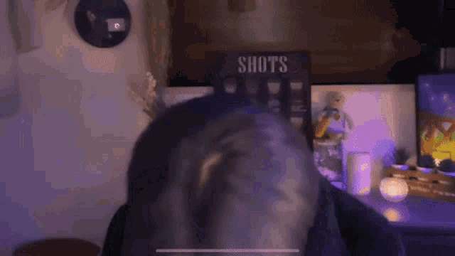 a person sitting in front of a sign that says " shots "