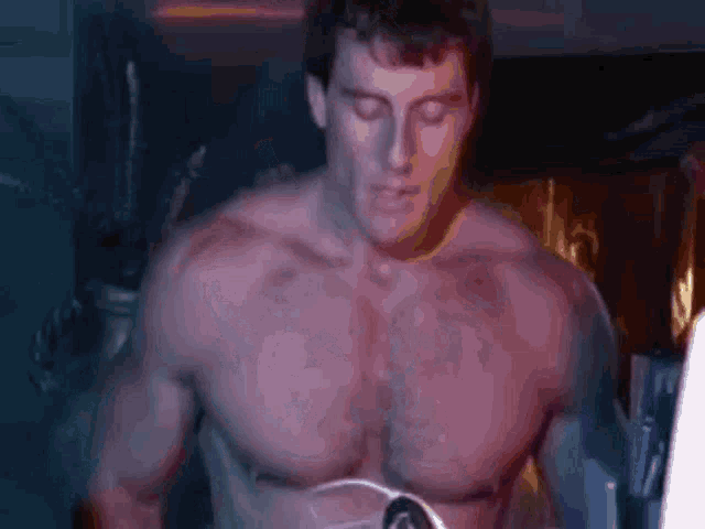 a shirtless man with his eyes closed is standing in a dark room