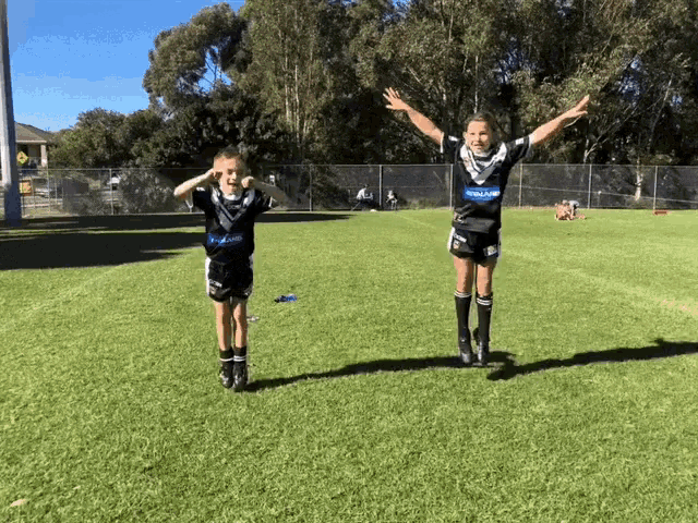 a boy and girl are jumping in the air on a field