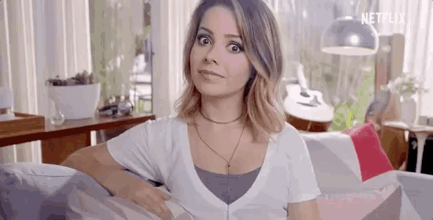 a woman is sitting on a couch in a living room and looking at the camera .