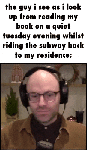 a man wearing headphones looks up from reading a quiet book on tuesday evening
