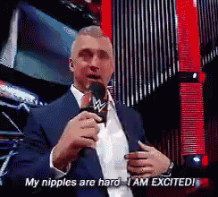 a man in a suit and tie is holding a microphone and saying my nipples are hard i am excited .