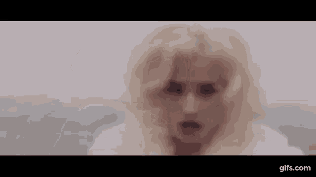 a woman with blonde hair is wearing a white fur coat and looking at the camera .