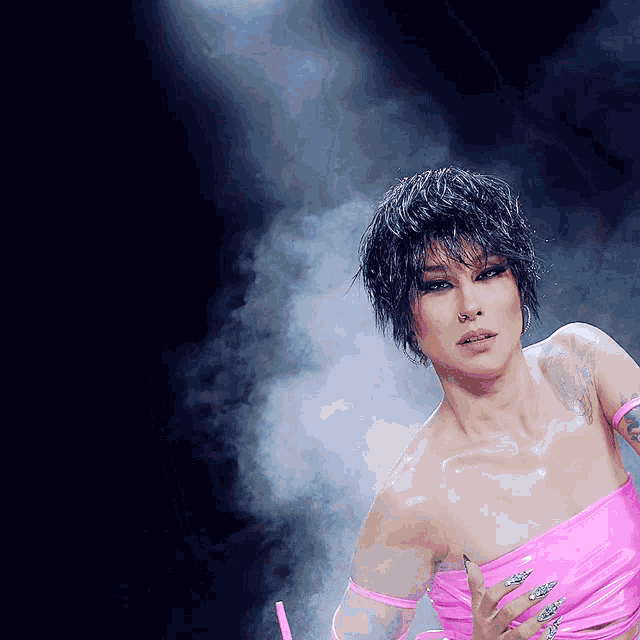 a woman in a pink dress stands in front of a smokey background