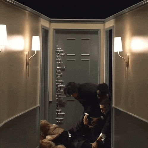 a group of people standing in a hallway with a door that has the letter l on it
