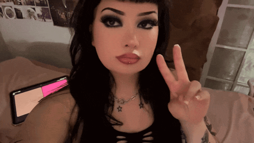 a woman is giving a peace sign in front of a tablet