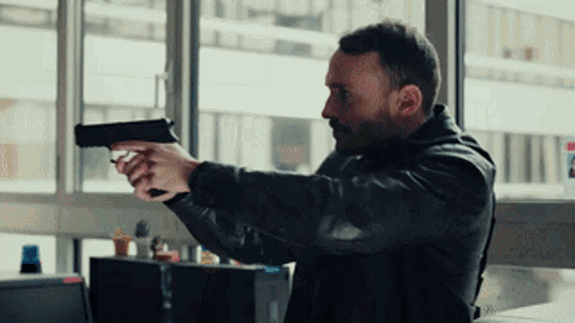 a man in a black jacket is pointing a gun