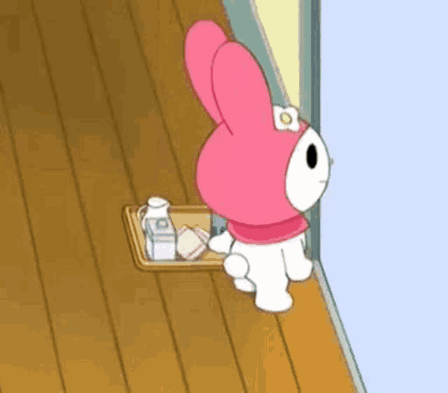 a pink bunny is standing next to a tray of food on a wooden floor .