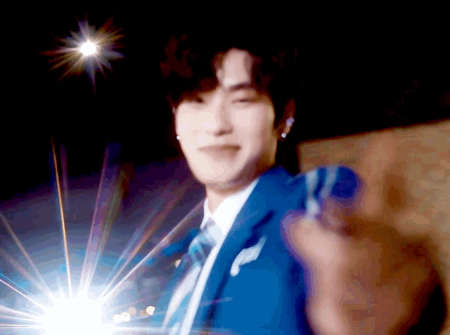 a man in a blue suit and tie is giving a thumbs up