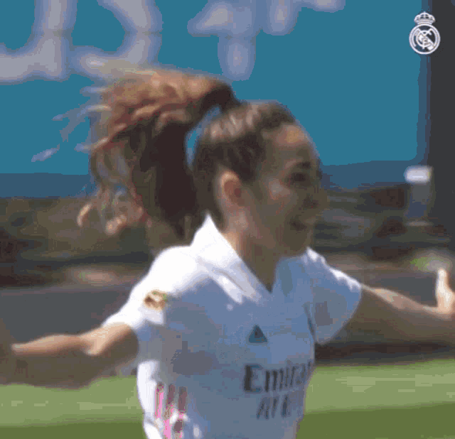 a female soccer player wearing a white jersey that says fly emirates